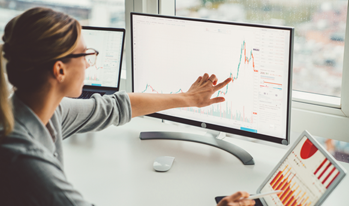 A woman consults financial data on a computer screen